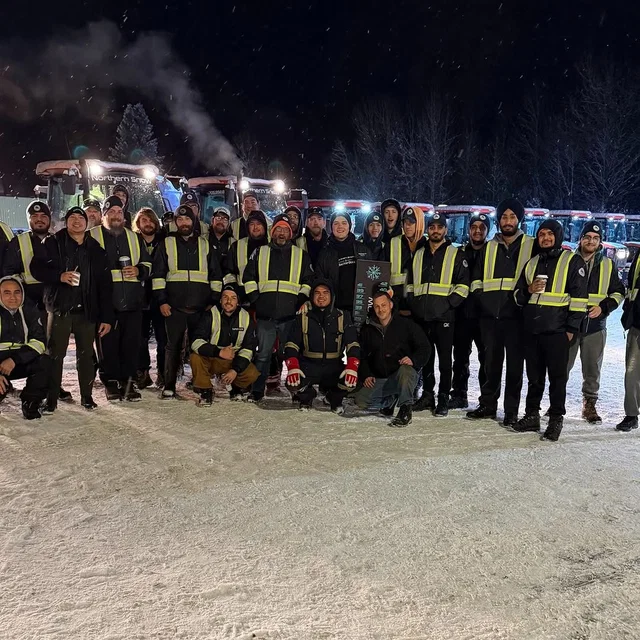 The Northern Snow crew lined up in front of their tractors on a snowy night